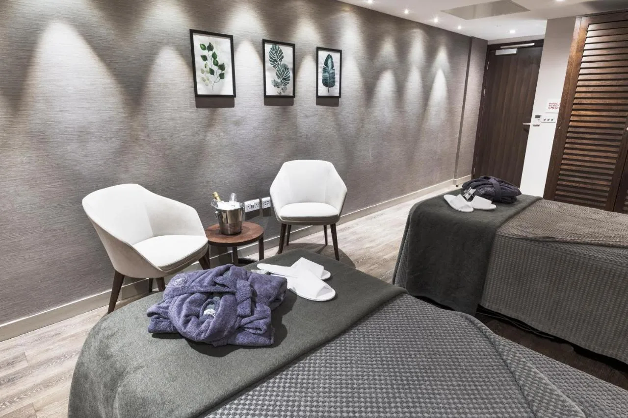 a treatment room with two beds and two chairs at Radisson Blu Hotel, Edinburgh City Centre in Edinburgh