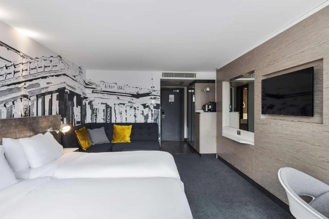 a hotel room with a bed and a couch at Radisson Blu Hotel, Edinburgh City Centre in Edinburgh
